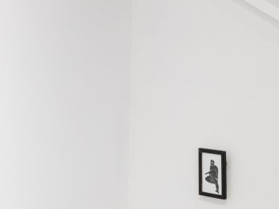group of prints one hanging the rest stacked in a corner