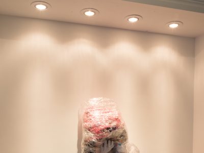 colourful asculture of female legs on a stage with half of male sticking out of wall
