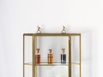 art installation of symetrical bottles and coloured liquid in a gold shelf