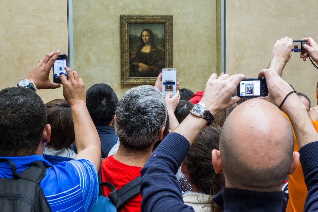 group of tourists taking pictures and standing in front of the Mona Lisa