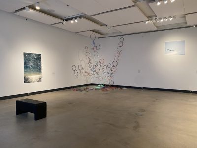 coloured hoop art installation with a painting and bench inside a gallery