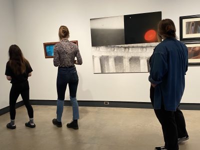3 gallery attendees viewing abstract paintings