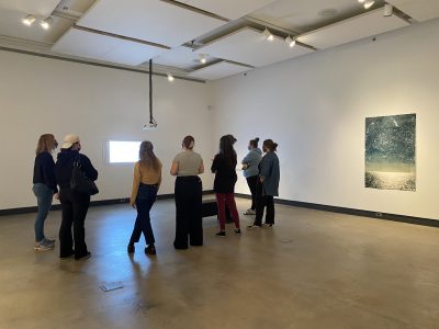 7 gallery attendees viewing projection on a wall