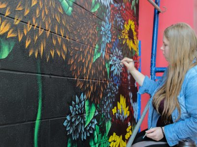 Fourth-year Visual Arts student Chardon Trimble-Kirk painting mural