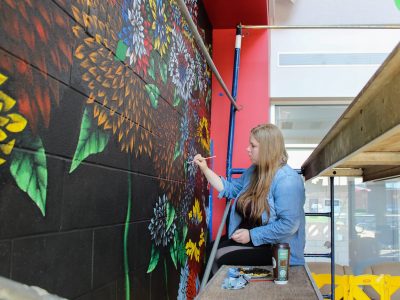 Fourth-year Visual Arts student Chardon Trimble-Kirk painting mural
