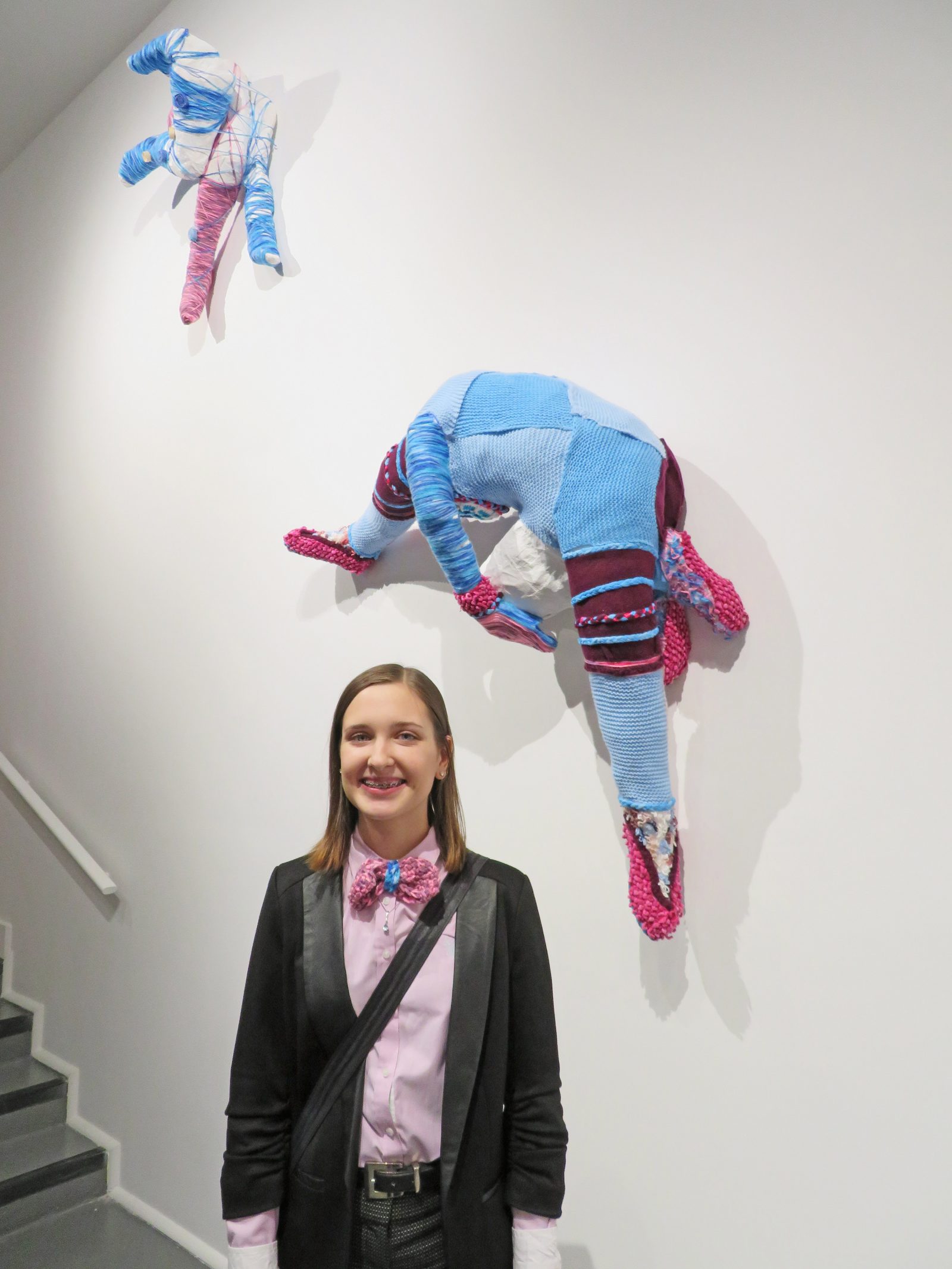 Visual arts graduate Victoria Reid with artwork hanging on wall at Rodman Hall