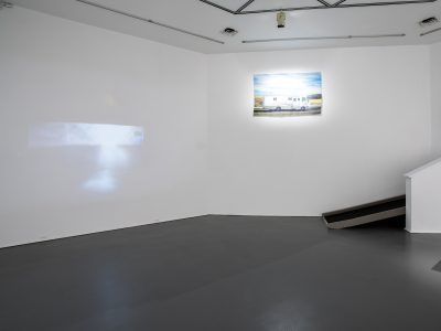 interior view of a gallery space with an artwork projection on a bare wall