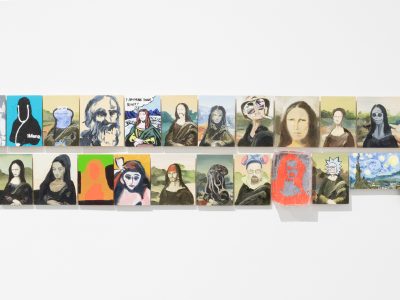 group of various arwork portraits hanging closely together on wall