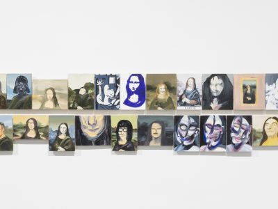 group of various arwork portraits hanging closely together on wall
