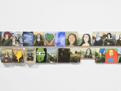 group of various arwork portraits hanging closely together on wall