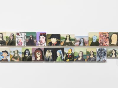 group of various arwork portraits hanging closely together on wall