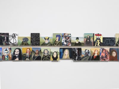 group of various arwork portraits hanging closely together on wall