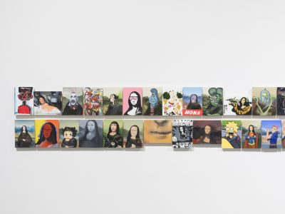 group of various arwork portraits hanging closely together on wall