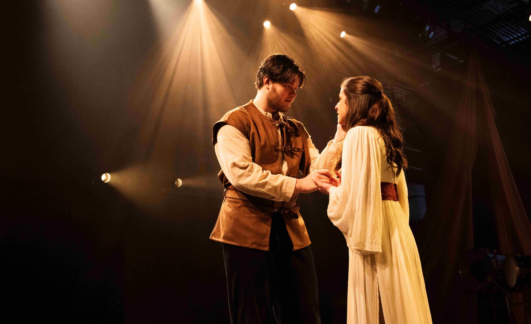 Two student performers on a stage below spotlights. 