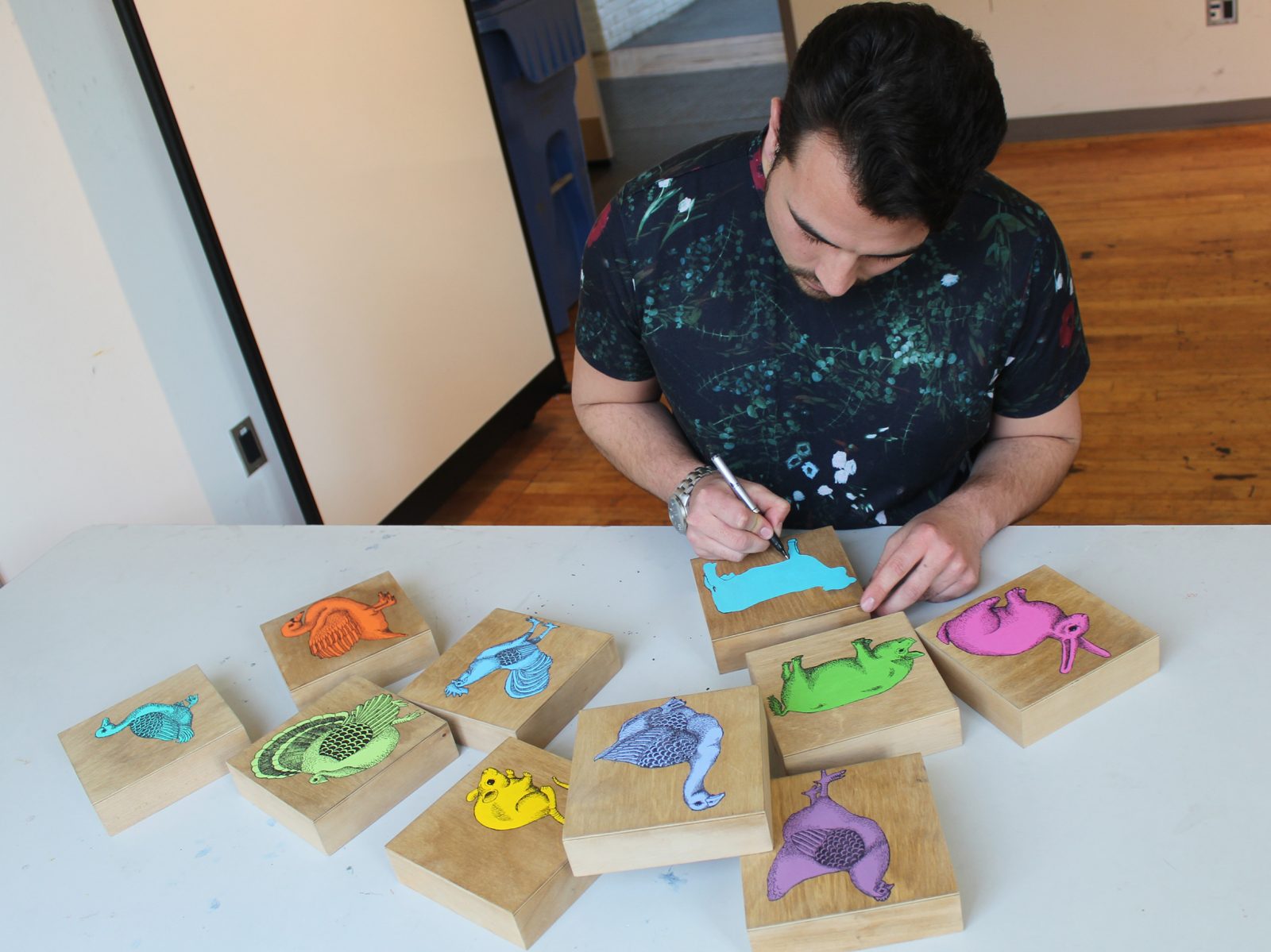 Connor Playfair painting colourful dinosaurs on wooden cubes