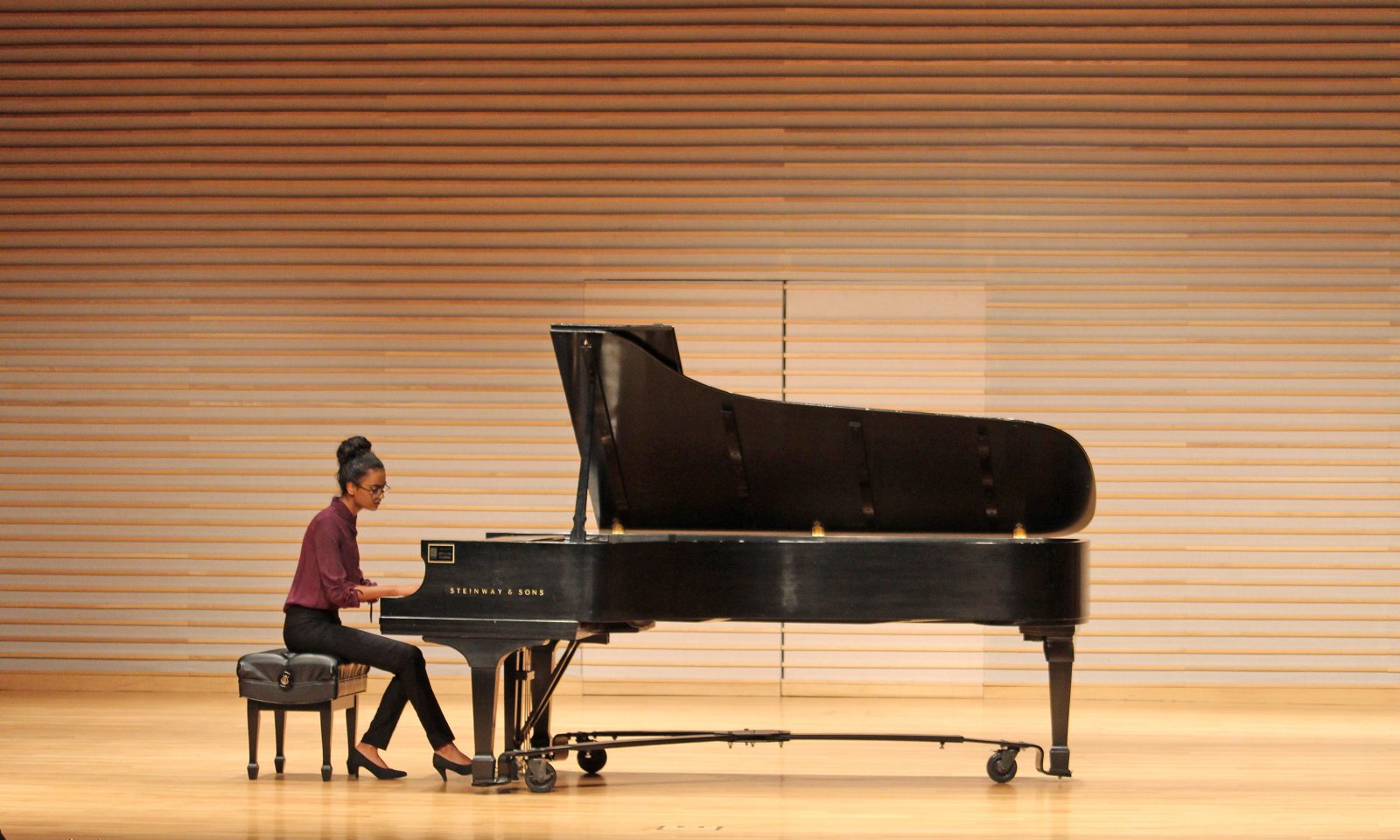 Brock Music student Divya Iyer is seen on stage playing piano.