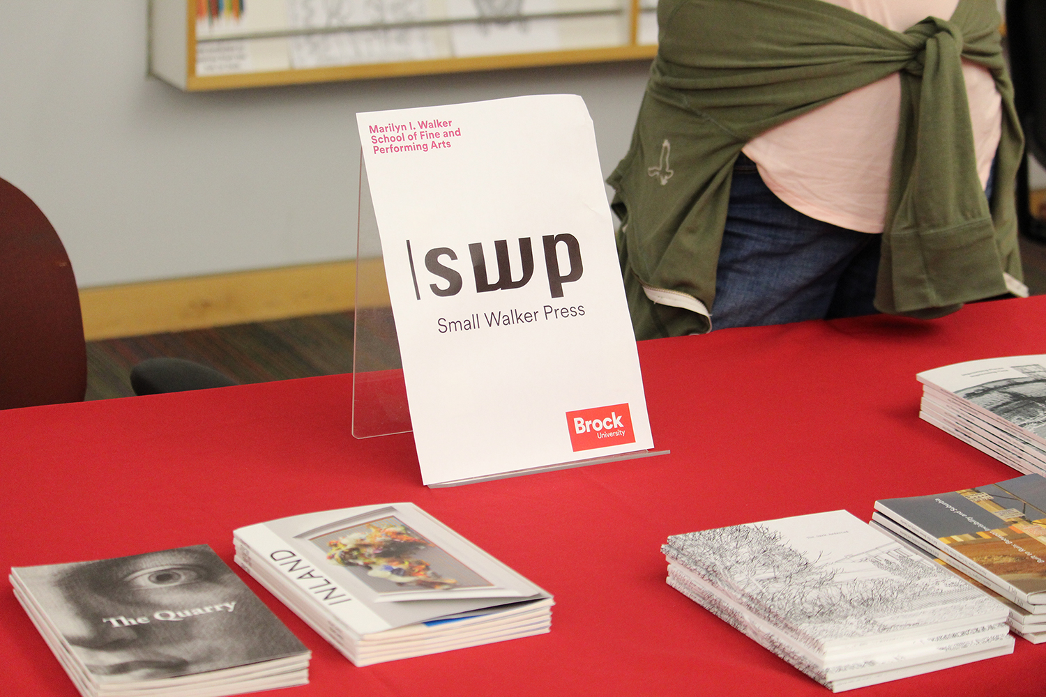 A tabletop banner reads “SWP Small Walker Press” set atop a red table cloth with a collection of books and publications.