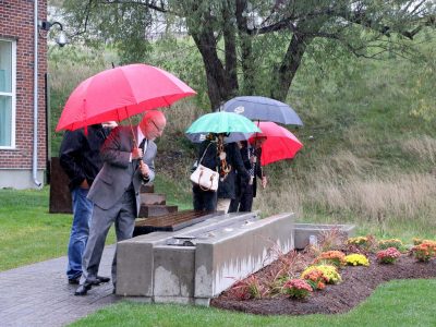 People with umbrellas viewing the Rotary Reflecting Pool water feature outside of Brock University's Marilyn I. Walker School of Fine and Performing Arts
