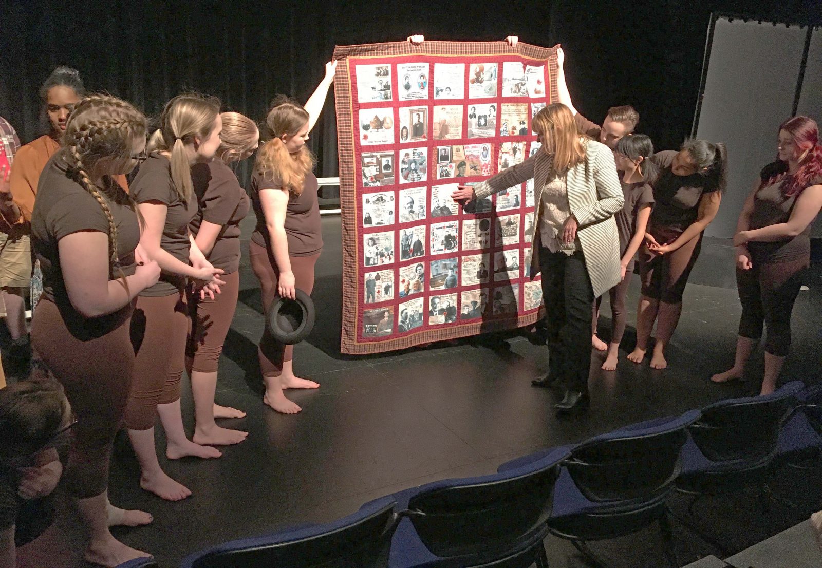 students and professor on stage in front of In-the-soil quilt
