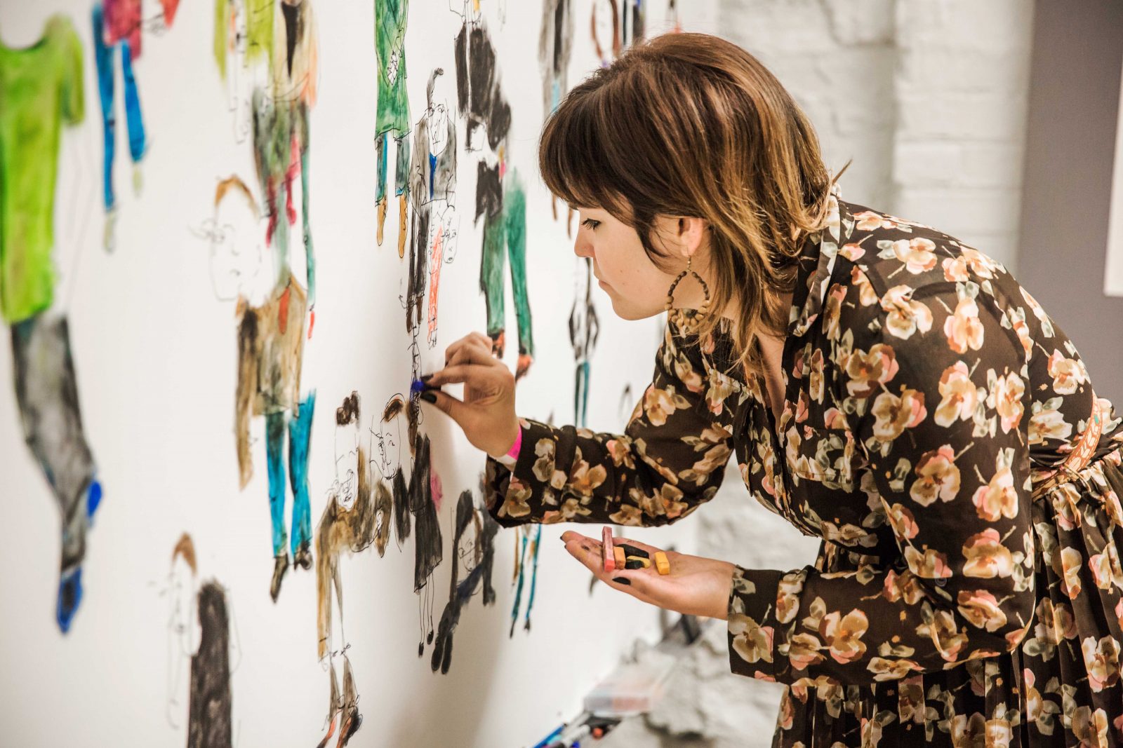 artist drawing characters on wall in pastels