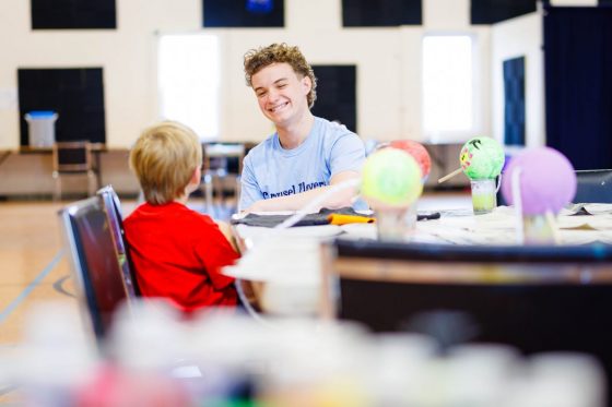 Photo of Liam Farrell laughing with a child at a Carousel Players camp.