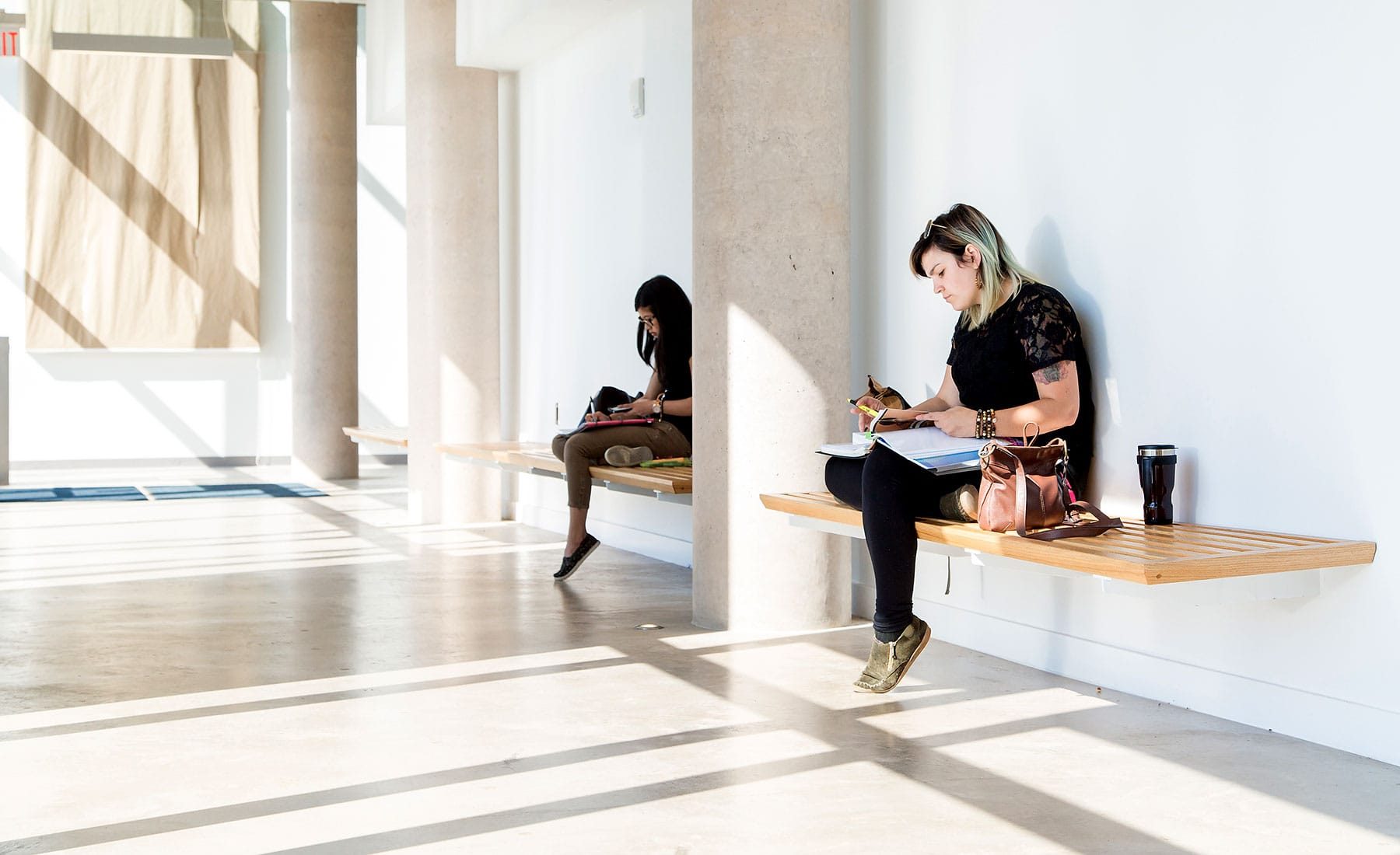 2 seated students at hallways Brock University downtown campus
