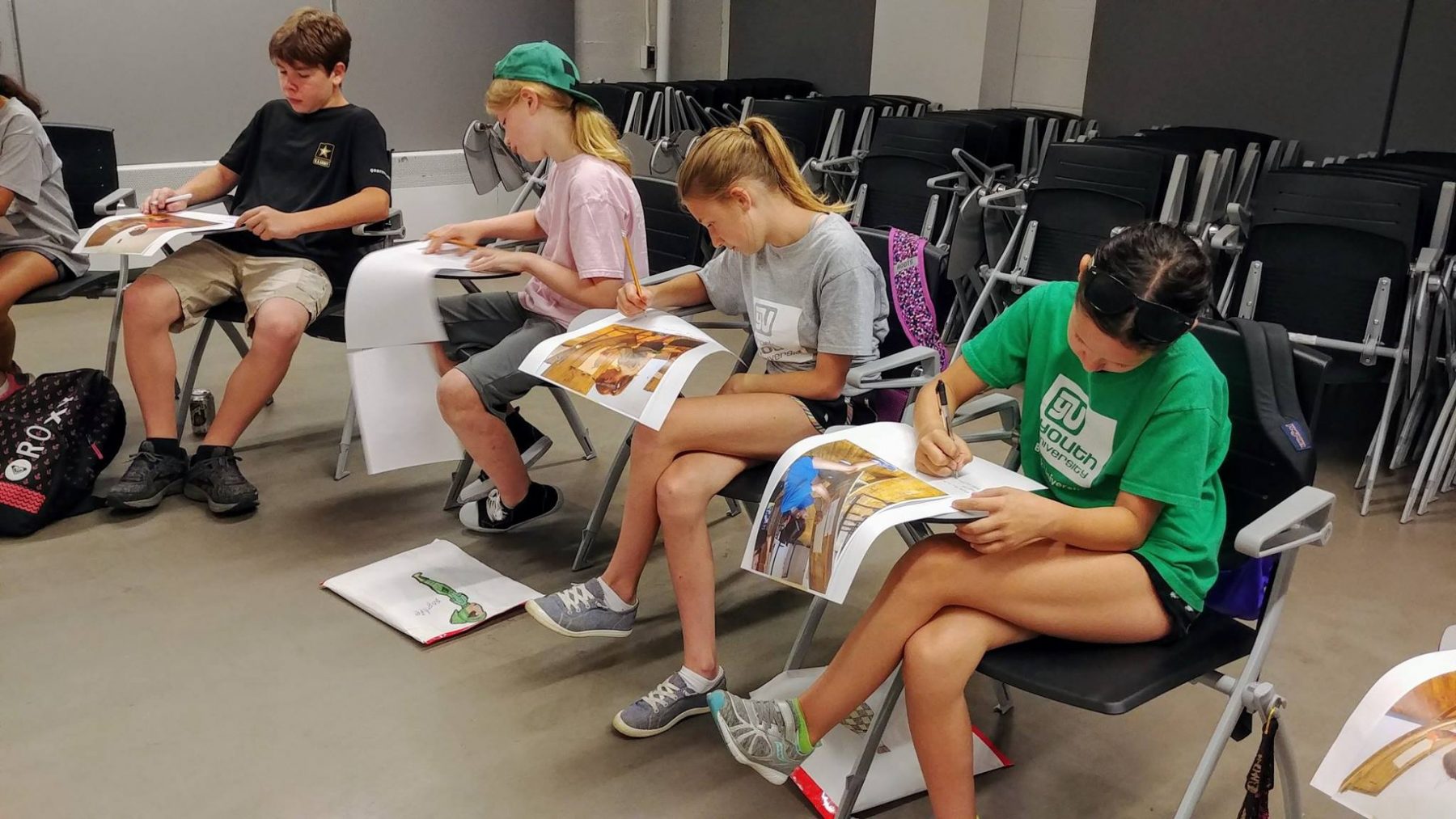 Brock youth university students siting on chairs writing on paper with photographs