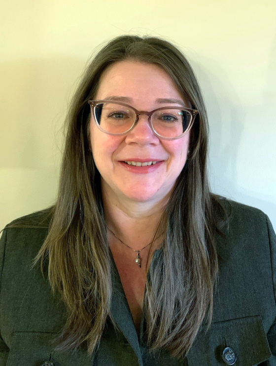 headshot of woman with long brown hair wearing glasses smiling