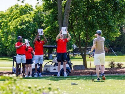 Brock athletes holding up numbered signs rating a golfer