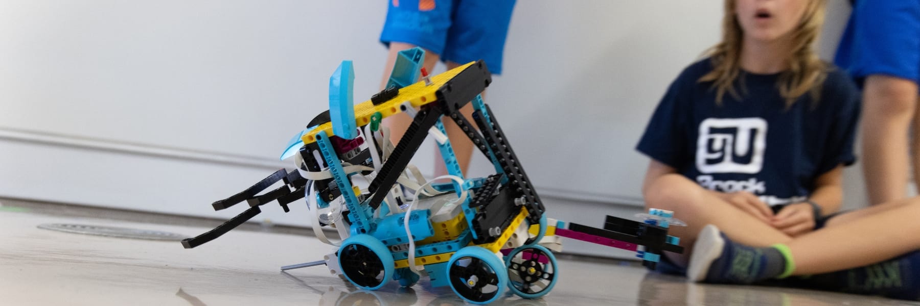 closeup of a lego robot with a child in background controling it
