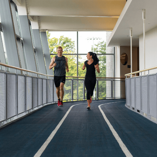 2 students running on indoor track