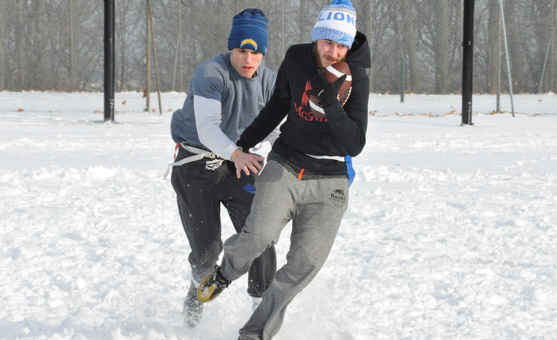 2 students playing flag football in the snow 