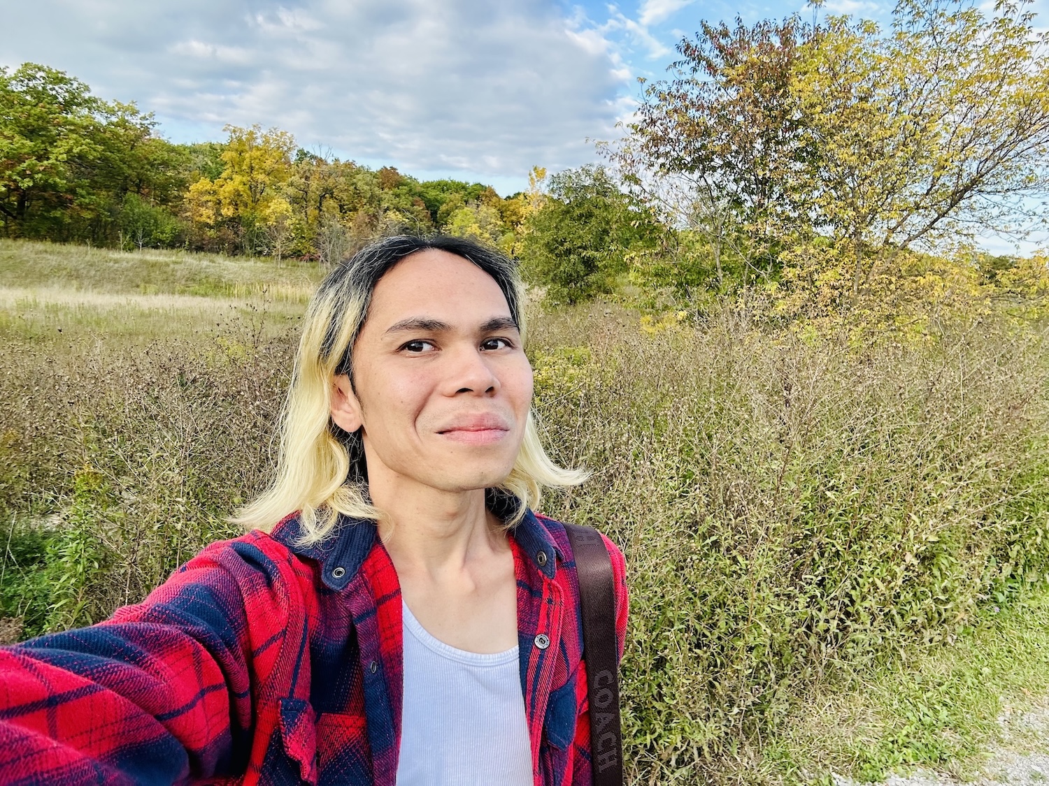 A person standing in an open field with trees in the background.