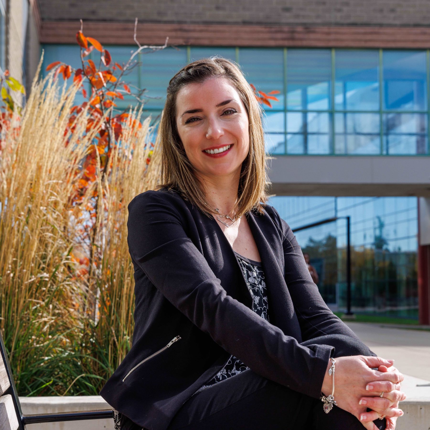 A woman sitting on a bench with Brock University's main campus in the background.