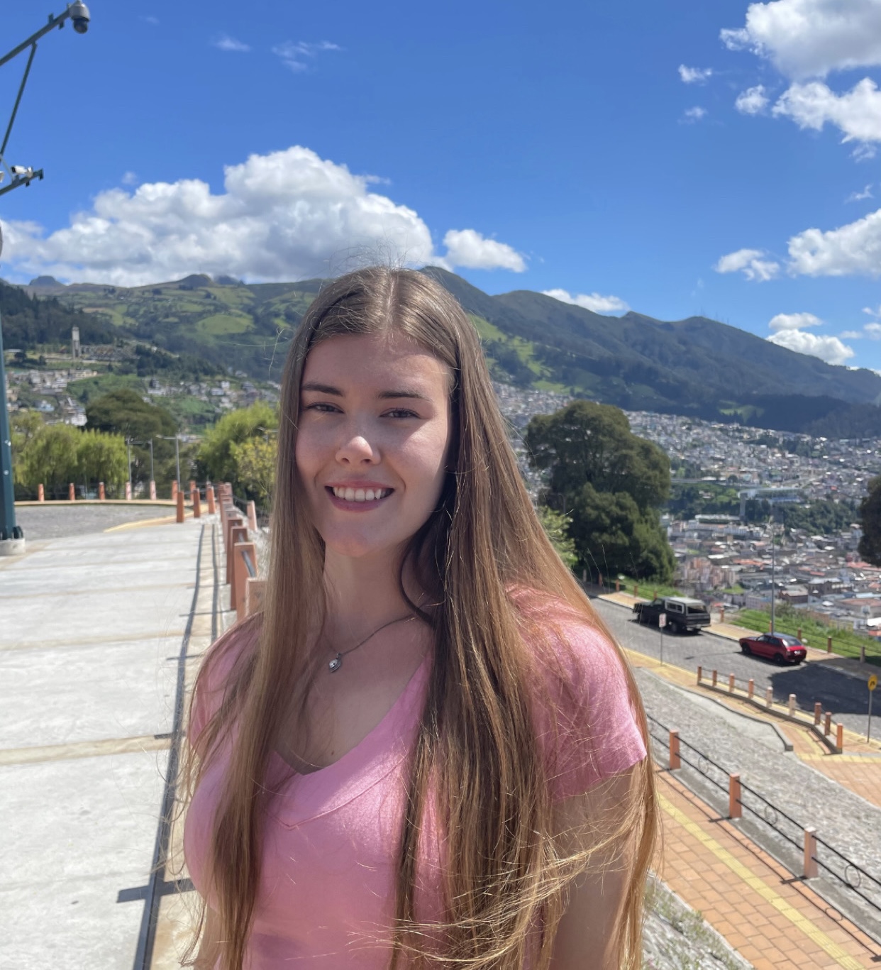 Kayla Hoyos Lewis standing on a road with a city and mountains in the background.