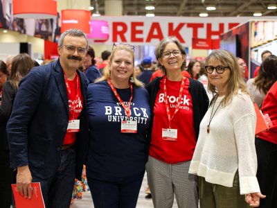 4 people pose for a photo. 3/4 of wearing Brock branded shirts.