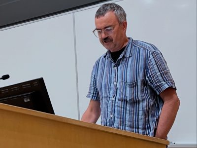 A Man in a blue shirt standing behind a podium on stage.
