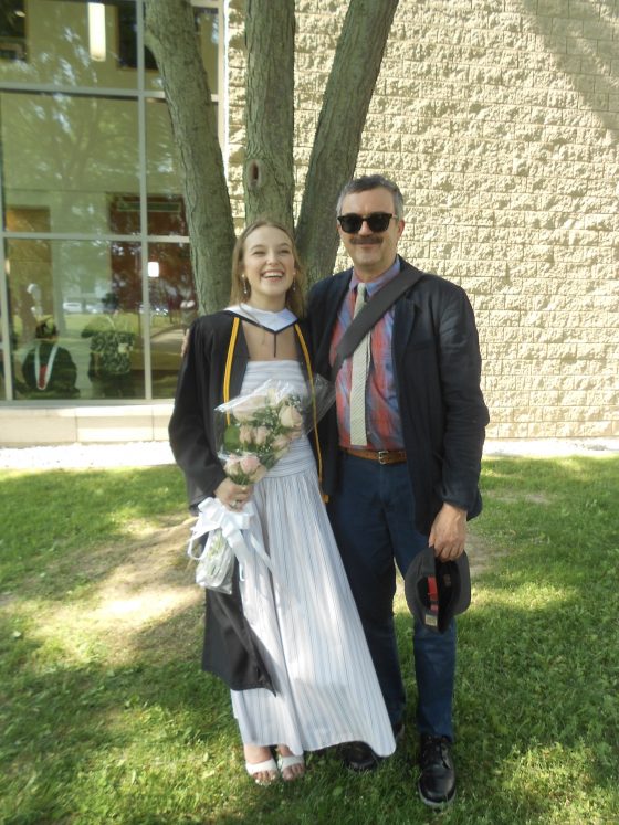 Brock University CPCF graduate Chloe Pasco in a graduation gown and holding a bouquet of flowers, standing next to Associate Professor Anthony Kinik.