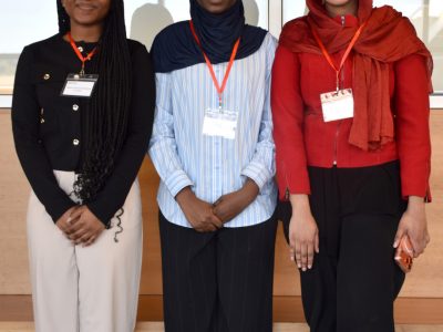 Three students in professional attire pose for a photo.