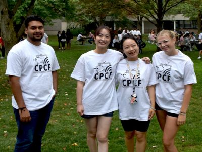 4 Students pose for a photo. They are all wearing match white t-shirts with 