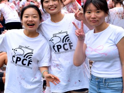 Three smiling students pose for a photo before the grap stomp starts. they are wearing clean white 