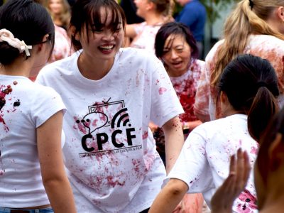 A smiling student stomps through grapes in a crowd of other students. Their white 