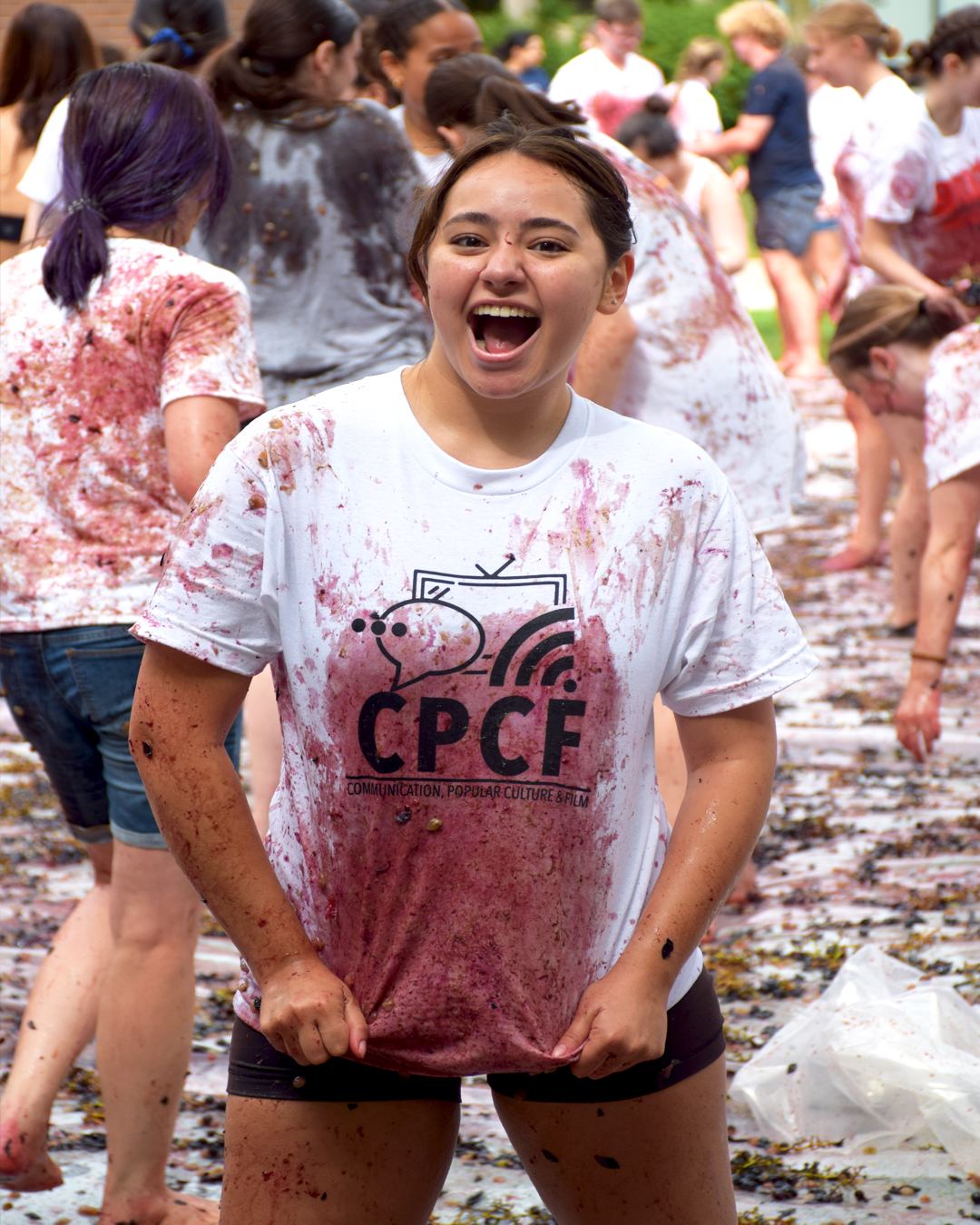Student pulls on their t-shirt to reveal CPCF Logo and Grape Stains