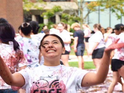 A sliming student tosses grapes up in the air. Their once white 
