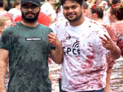 2 students pose for a photo after they have participated in the Grape Stomp. The once white 