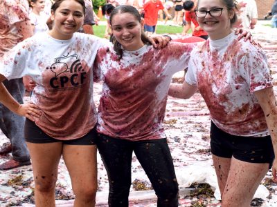 3 students pose for a photo after they have participated in the Grape Stomp. Their once white 