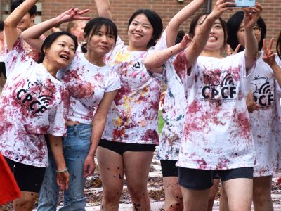 A group of students cluster together to take a selfie after they have participated in the Grape Stomp. Their once white 