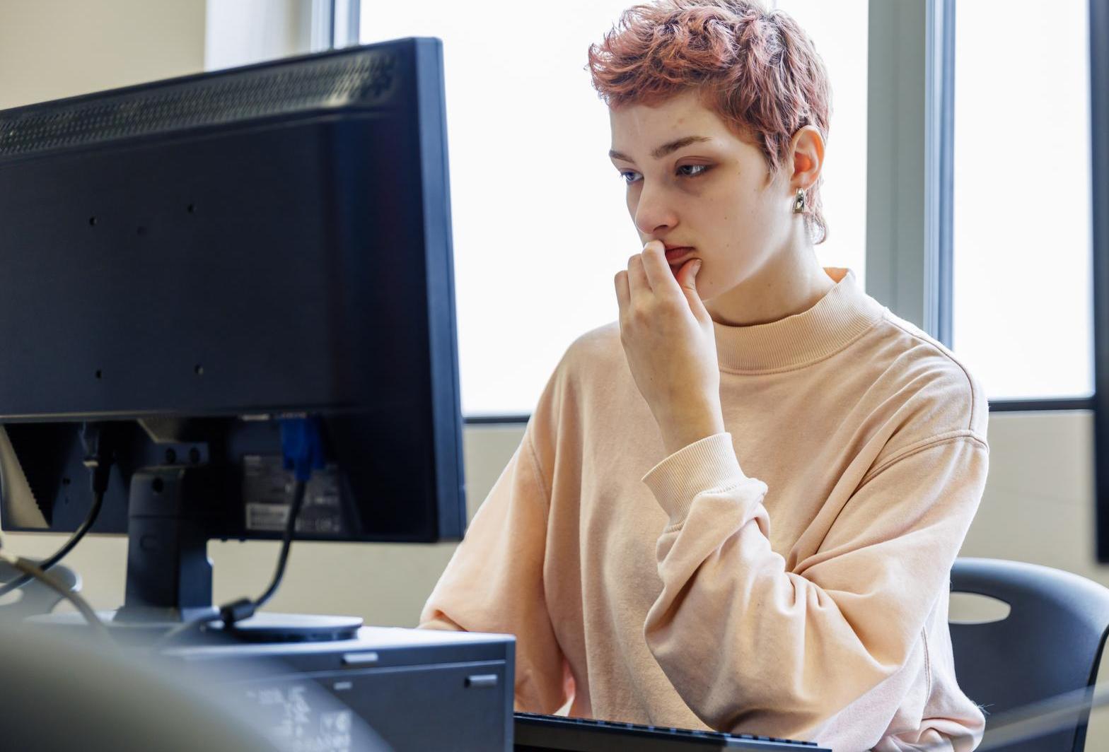A student looks at a computer screen with an unsure look.