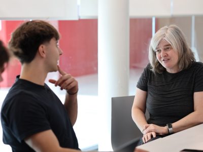 A profesor talking to two students at a a table