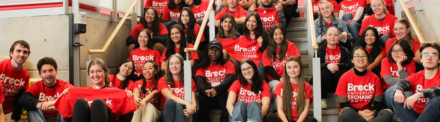 A group of students in Brock University Exchange Program shirts sitting on a staircase.